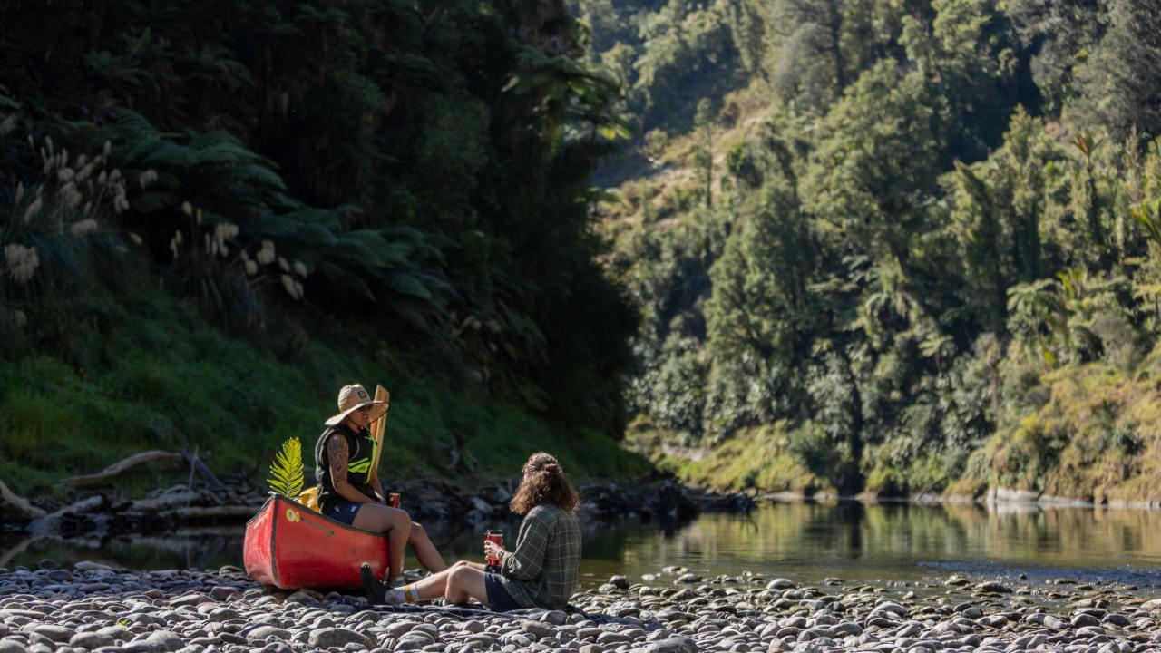 Paddlers pause for a rest on the riverbank of Te Whanganui Awa