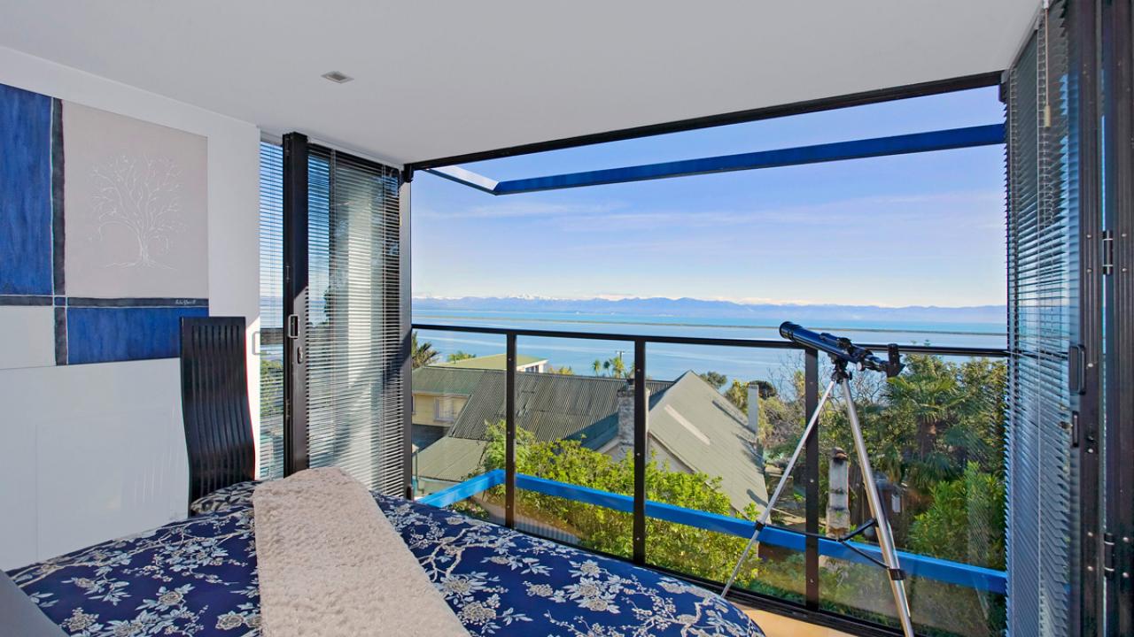 Master bedroom with Queen bed facing full-length glass bi-folds with fantastic sea views. Above a tinted skylight allows a view of the stars.
