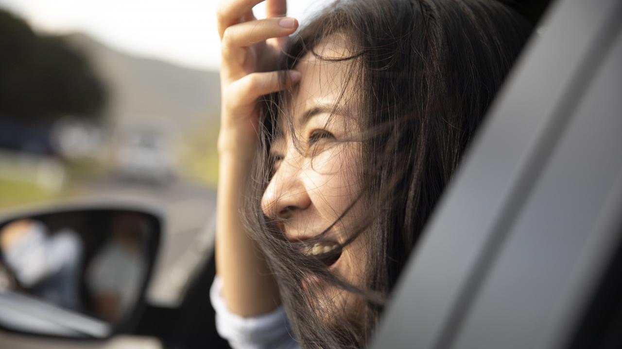 A woman smiling looking outside the passenger car window.