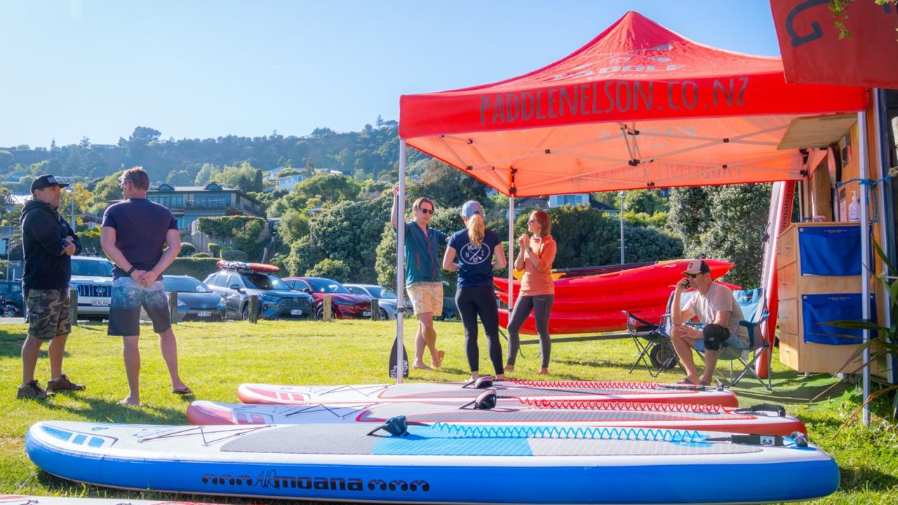 Paddle Nelson Base at Tāhunanui Beach, with paddleboards and sit-on-top kayaks ready to hire.