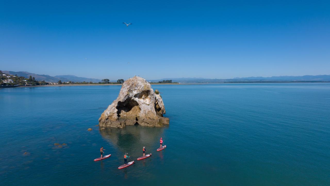 Paddleboarding to Urenui (Fifeshire Rock) at Tāhunanui Beach.