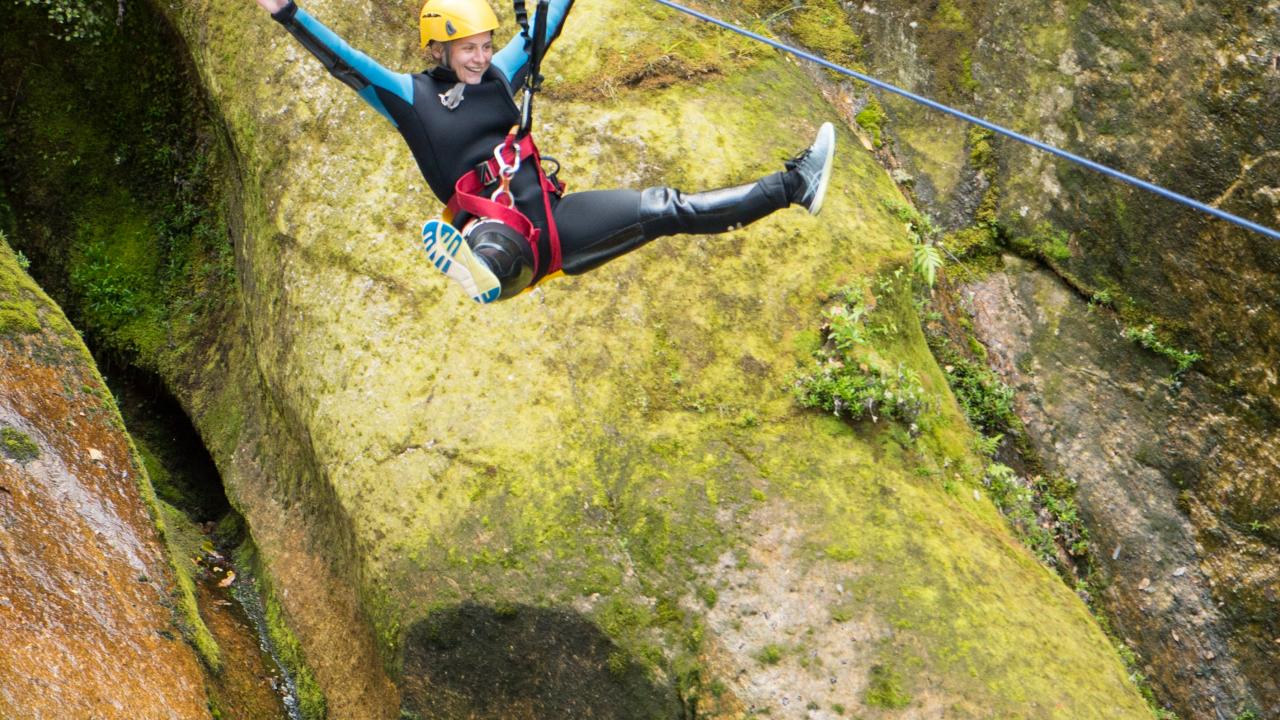 Flying high on a zipline over waterfalls.