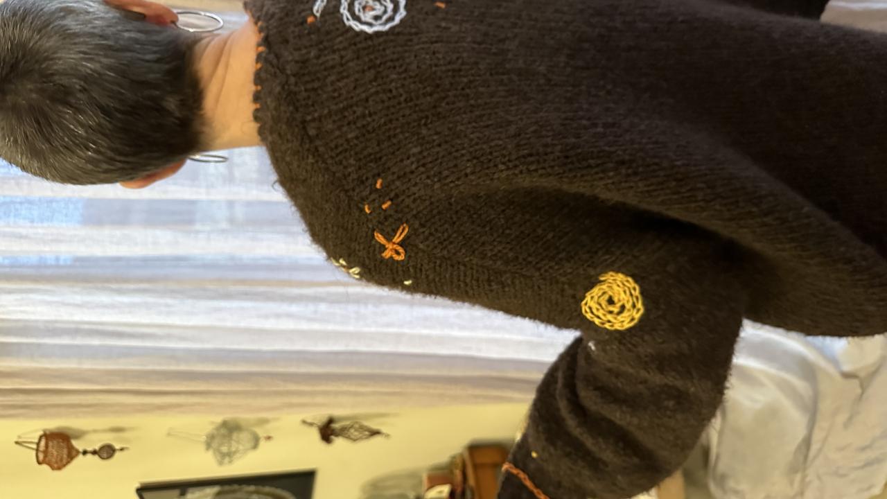 The tutor of the Embellish Me Workshop shows off their example embellishments on a cardigan.