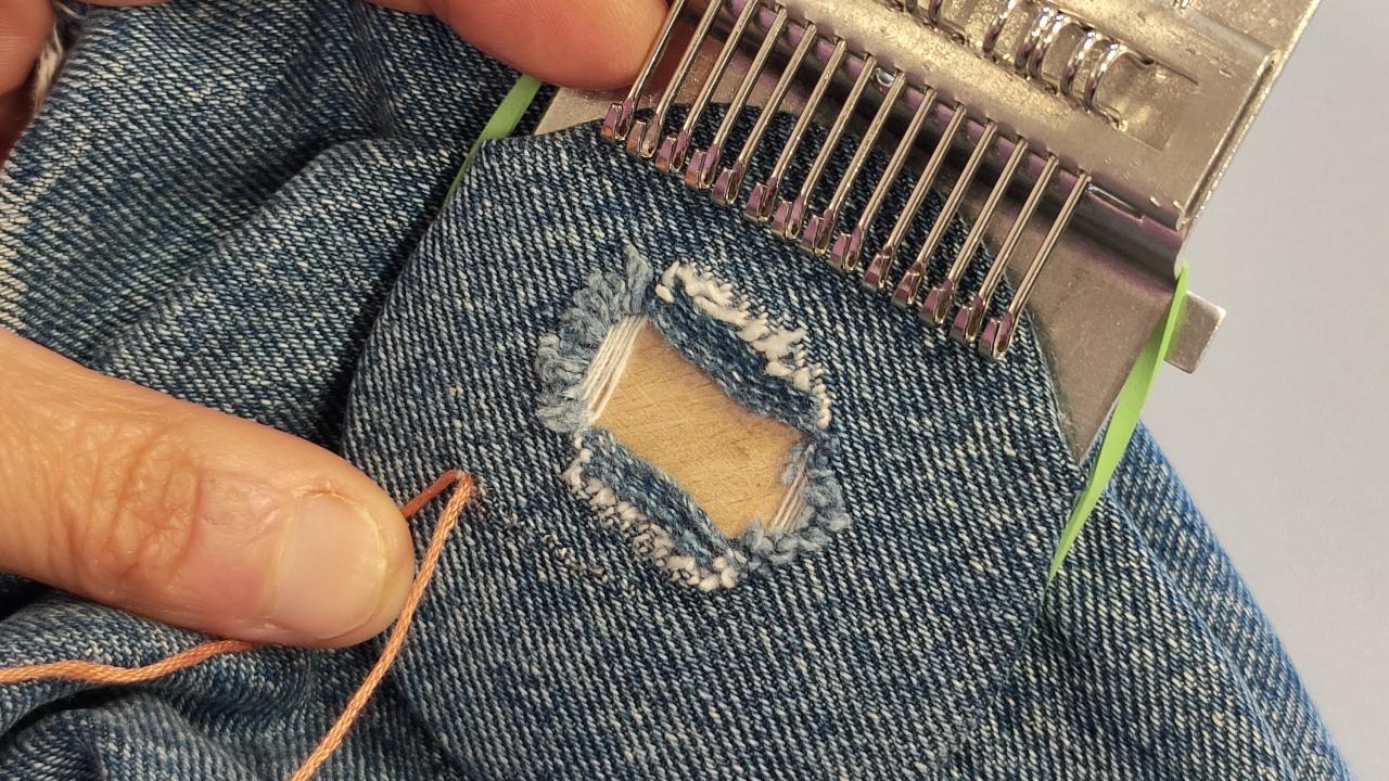 A student repairs a hole in a pair of jeans at their Visible Mending with a Speedweve Darning Loom Workshop.