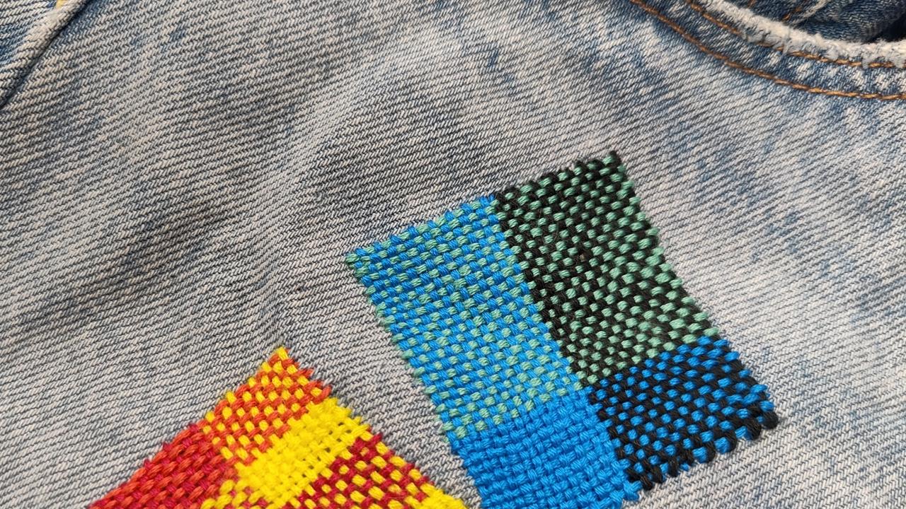 A students work repairing a hole in a pair of jeans at their Visible Mending with a Speedweve Darning Loom Workshop.