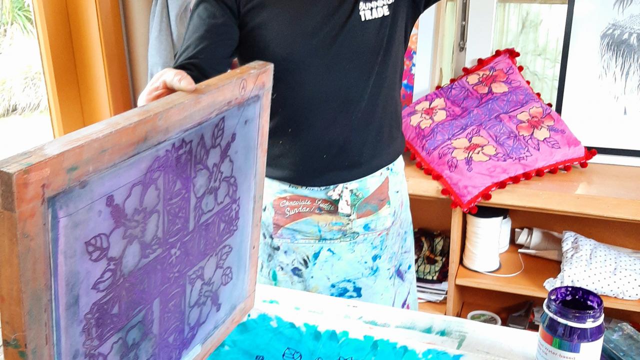 A student prints their own design onto fabric and paper at their Mates Screen Printing on T-Shirts Workshop.