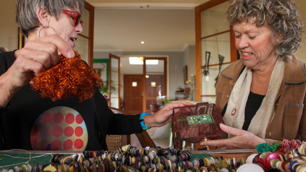 A student works with their tutor on a piece of art at their Transformational Textiles Workshop.