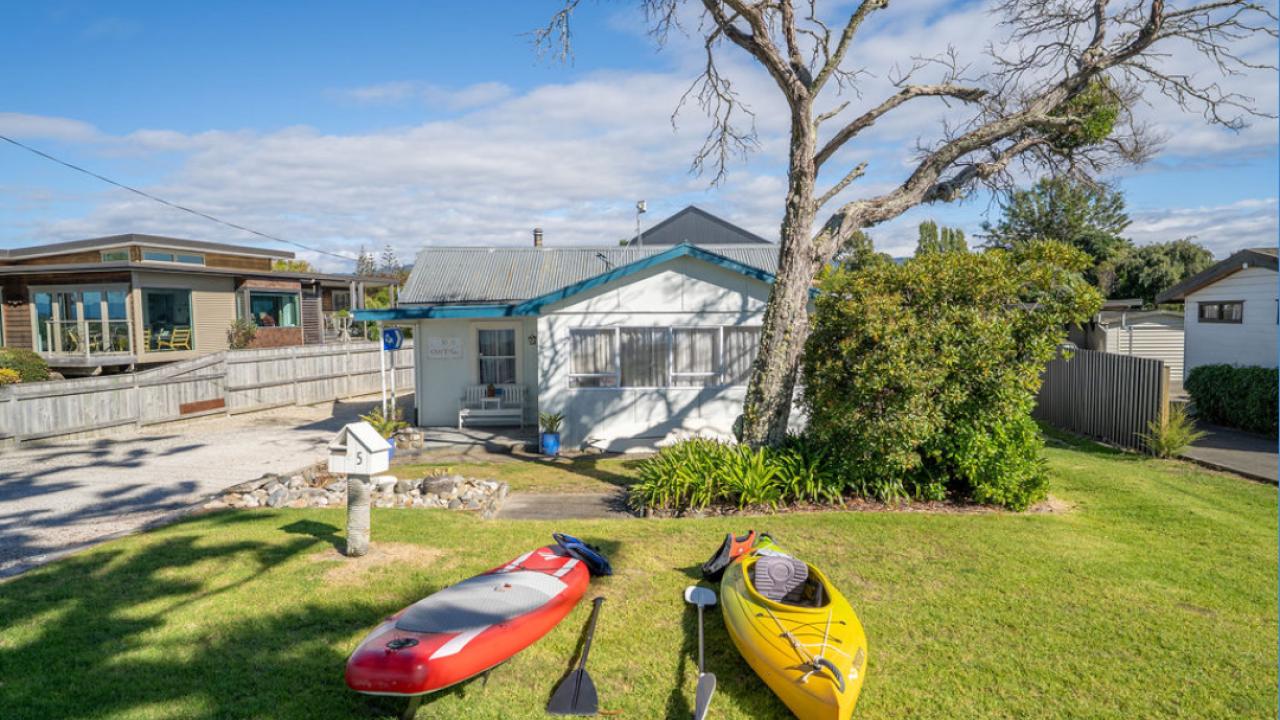 The cottage from the front with kayak and stand up paddle board