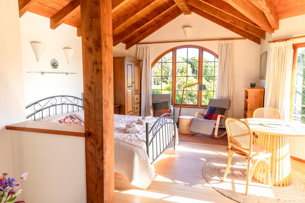 A spacious, open-plan interior with a high-pitched ceiling and living area crafted with locally sourced macrocarpa timber & ceramic tiles. Simone Jackson